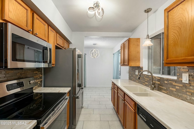 kitchen featuring appliances with stainless steel finishes, sink, decorative backsplash, hanging light fixtures, and light tile patterned floors