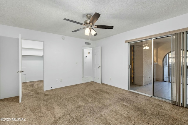 unfurnished bedroom featuring light carpet, ceiling fan, a closet, and a textured ceiling