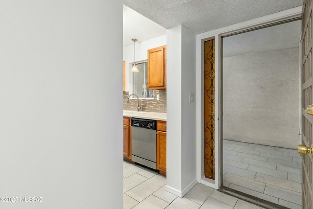 kitchen with light tile patterned flooring, decorative light fixtures, sink, backsplash, and stainless steel dishwasher