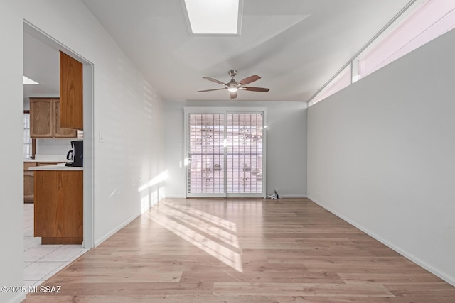 unfurnished living room with ceiling fan, lofted ceiling, and light wood-type flooring