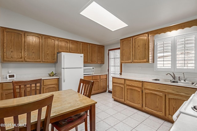 kitchen featuring vaulted ceiling, sink, light tile patterned flooring, and white appliances