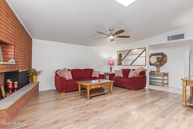 living room with ceiling fan, light hardwood / wood-style floors, lofted ceiling, and a fireplace