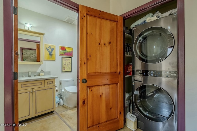 washroom featuring light tile patterned floors and stacked washer and clothes dryer