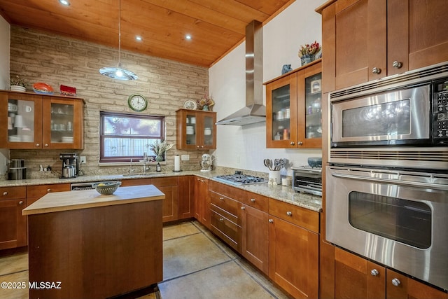 kitchen with sink, wall chimney exhaust hood, light stone countertops, wood ceiling, and stainless steel appliances