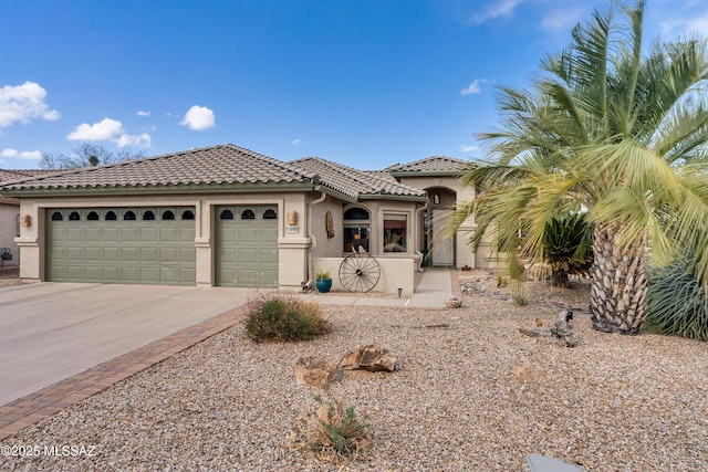 989 N Rhodes Dr, Green Valley, AZ 85614 - mediterranean / spanish-style home featuring a garage, concrete driveway, a tiled roof, and stucco siding