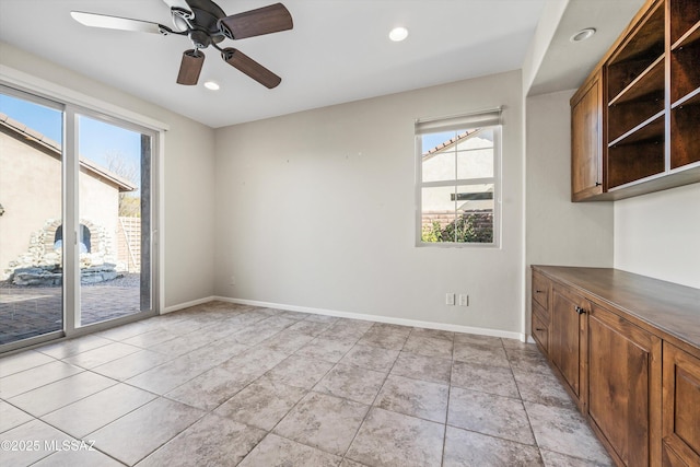 empty room featuring ceiling fan, light tile patterned flooring, and a wealth of natural light