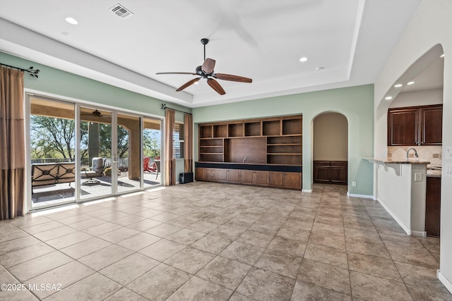 unfurnished living room featuring light tile patterned flooring and a raised ceiling