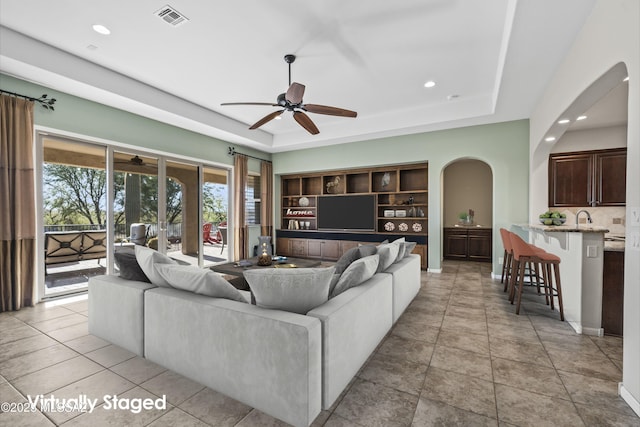 tiled living room with built in shelves and a tray ceiling