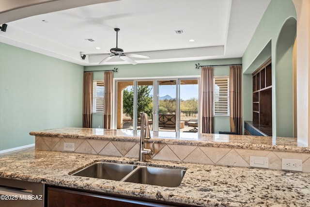 kitchen featuring sink, dishwasher, a raised ceiling, ceiling fan, and decorative backsplash