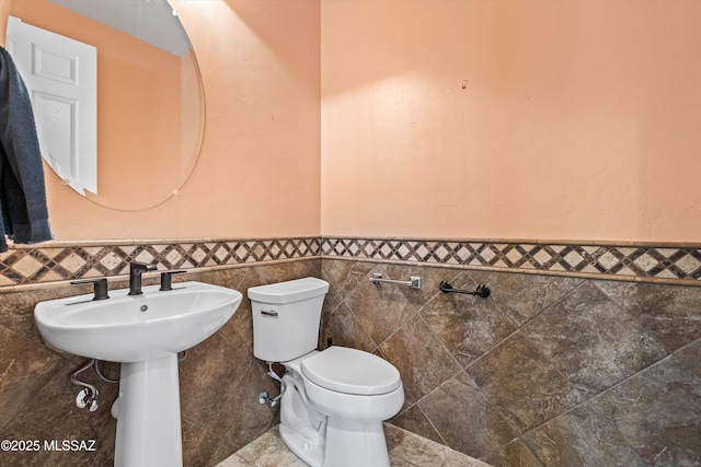 bathroom with tile walls, toilet, and sink