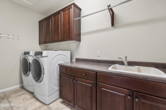 clothes washing area with washing machine and dryer, cabinets, and sink