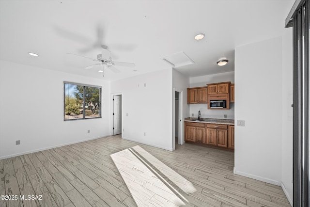 unfurnished living room with sink, ceiling fan, and light hardwood / wood-style floors