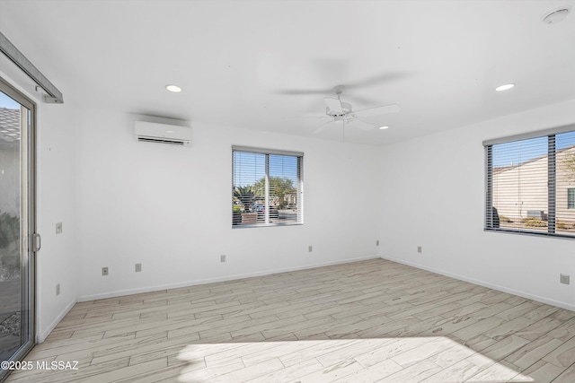 spare room featuring light wood-type flooring, a wall unit AC, and a wealth of natural light