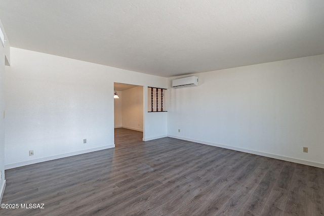 empty room featuring a wall mounted air conditioner and dark hardwood / wood-style floors