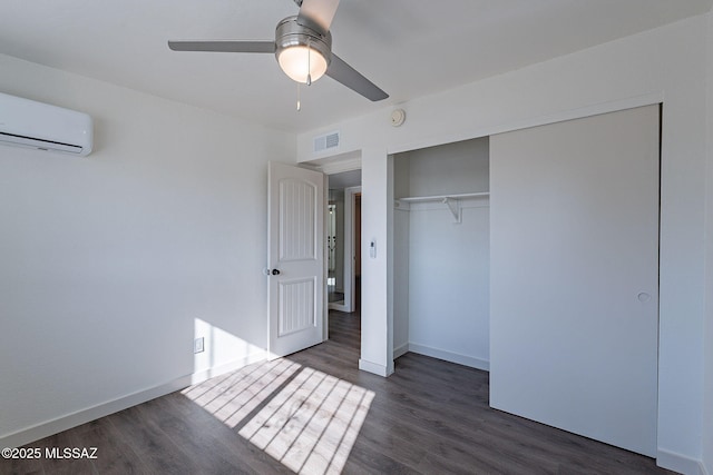 unfurnished bedroom featuring a wall mounted AC, ceiling fan, a closet, and dark hardwood / wood-style floors