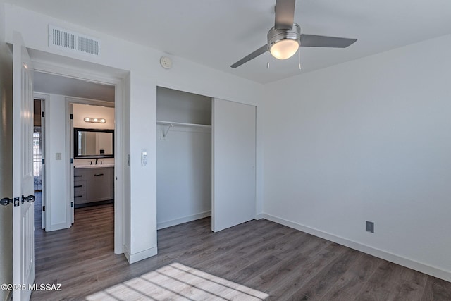 unfurnished bedroom featuring hardwood / wood-style flooring, ceiling fan, sink, and a closet