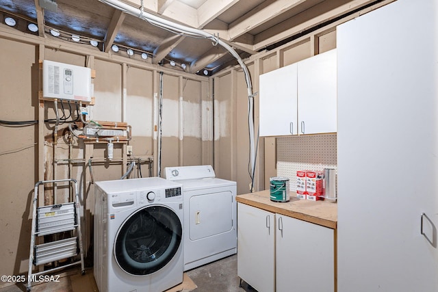 clothes washing area featuring washer and clothes dryer and cabinets