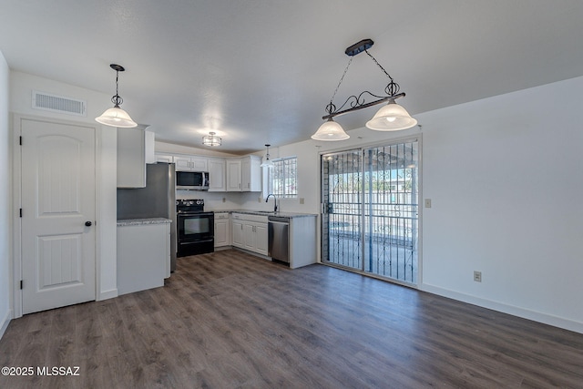 kitchen with appliances with stainless steel finishes, dark hardwood / wood-style flooring, sink, white cabinets, and hanging light fixtures