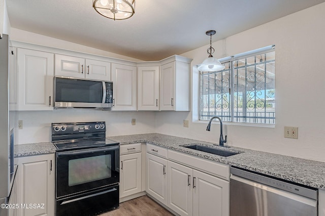 kitchen featuring sink, white cabinets, decorative light fixtures, and appliances with stainless steel finishes