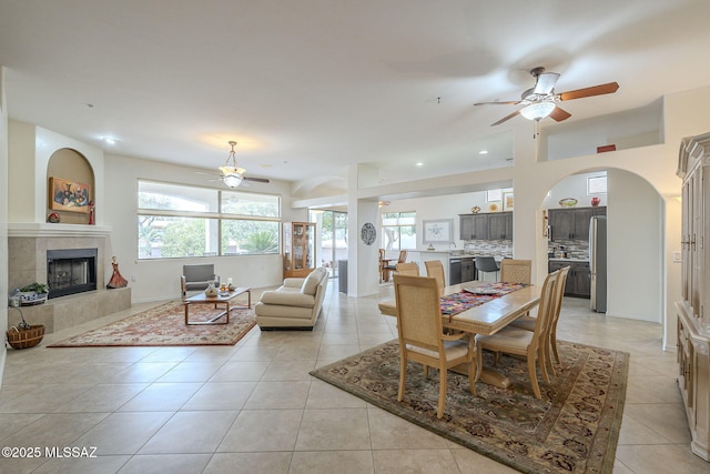 tiled dining space featuring ceiling fan and a tiled fireplace