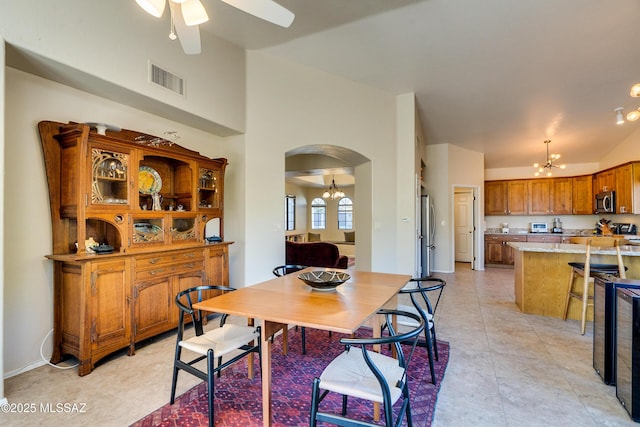 tiled dining room with ceiling fan with notable chandelier