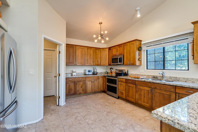 kitchen featuring lofted ceiling, sink, light stone counters, pendant lighting, and stainless steel appliances