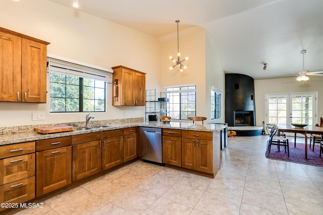 kitchen with sink, light stone countertops, decorative light fixtures, stainless steel dishwasher, and kitchen peninsula