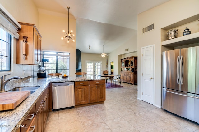 kitchen featuring light tile patterned flooring, sink, light stone counters, kitchen peninsula, and stainless steel appliances