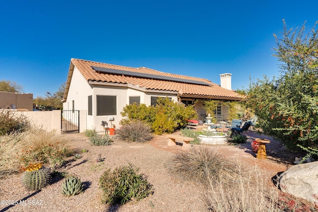 rear view of property featuring solar panels