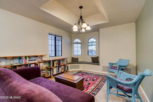 living area featuring a tray ceiling and a chandelier