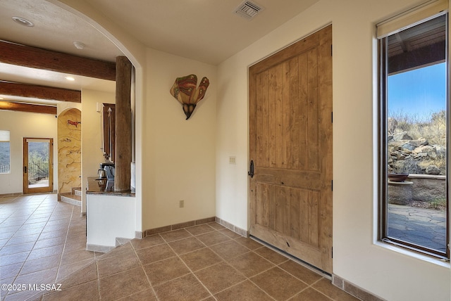 entryway with beamed ceiling and tile patterned flooring