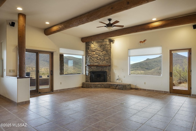 unfurnished living room featuring a mountain view, ceiling fan, beam ceiling, and a fireplace