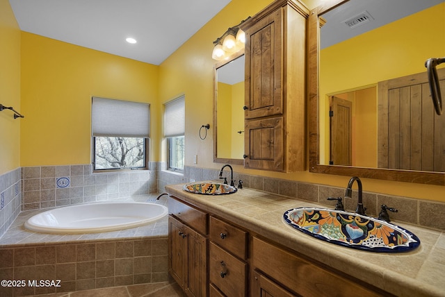 bathroom with vanity, a relaxing tiled tub, and tile patterned floors