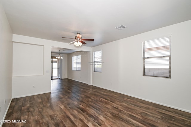 unfurnished room with ceiling fan with notable chandelier and dark hardwood / wood-style floors