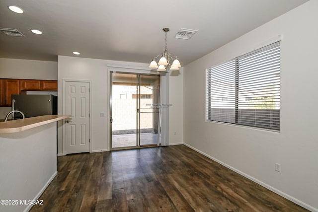 unfurnished dining area featuring dark wood-type flooring, a chandelier, and sink