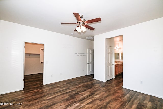 unfurnished bedroom with ensuite bathroom, ceiling fan, a closet, dark hardwood / wood-style floors, and a walk in closet