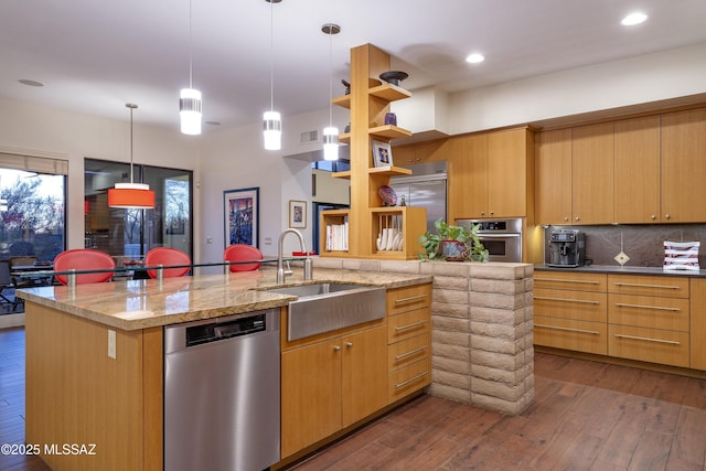 kitchen with dark hardwood / wood-style flooring, backsplash, stainless steel appliances, sink, and an island with sink