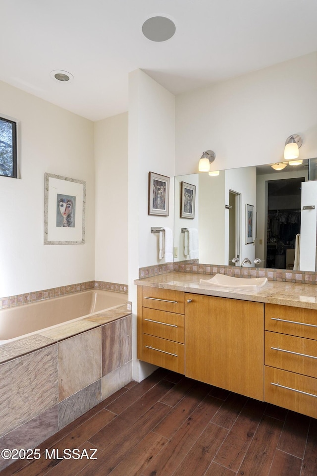 bathroom with tiled tub and vanity