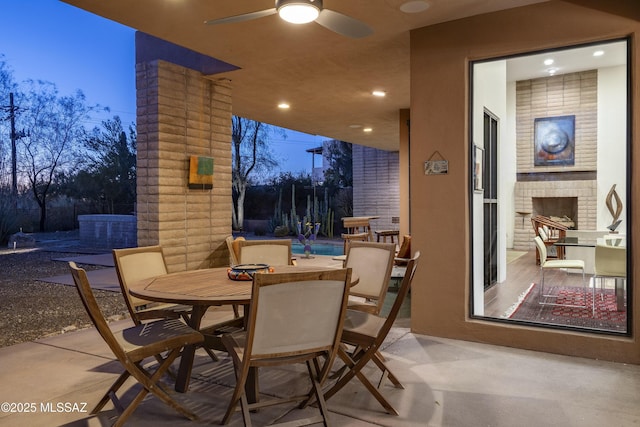 patio terrace at dusk featuring an outdoor brick fireplace and ceiling fan