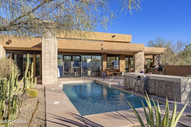 view of swimming pool with pool water feature, an outdoor kitchen, exterior bar, and a patio