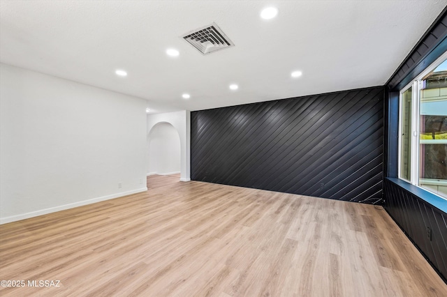 spare room with arched walkways, light wood finished floors, visible vents, and recessed lighting