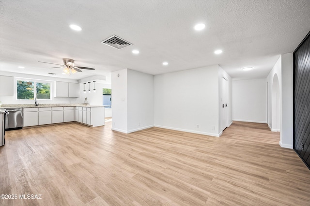 unfurnished living room with recessed lighting, visible vents, light wood-style flooring, a sink, and a textured ceiling