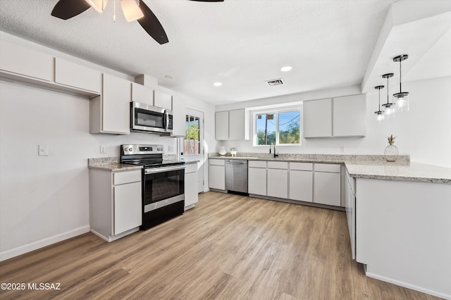 kitchen featuring visible vents, appliances with stainless steel finishes, hanging light fixtures, light countertops, and white cabinetry