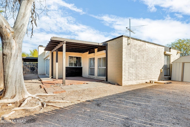 back of house with a shed and a patio area