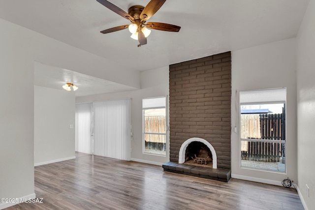 unfurnished living room featuring ceiling fan, wood-type flooring, and a fireplace