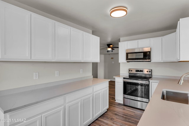 kitchen featuring ceiling fan, sink, dark wood-type flooring, stainless steel appliances, and white cabinets