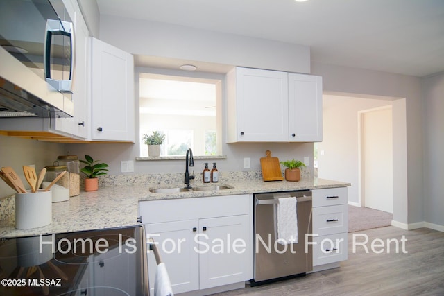 kitchen featuring white cabinets, appliances with stainless steel finishes, light stone counters, and sink