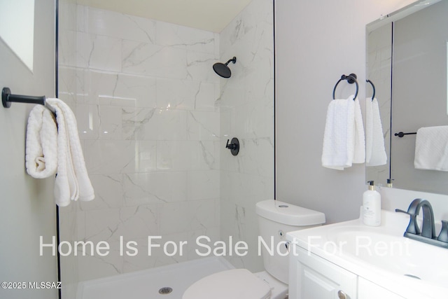 bathroom featuring tiled shower, vanity, and toilet