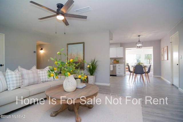 living room with ceiling fan with notable chandelier and light wood-type flooring