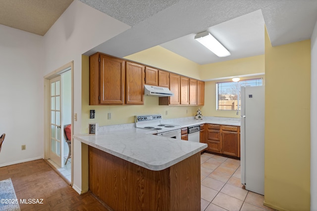 kitchen with white appliances, a textured ceiling, light tile patterned floors, and kitchen peninsula